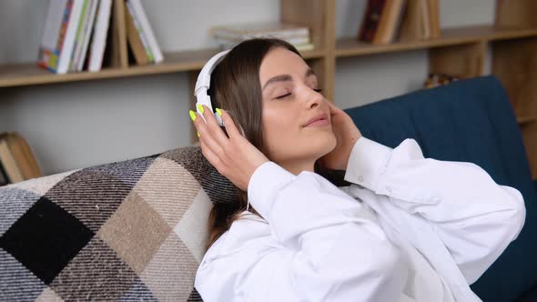 Head Shot Smiling Peaceful Woman Relaxing on Comfortable Couch Listening to Favorite Audio Music in