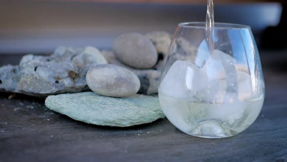 Wine being poured into a stemless glass filled with ice.