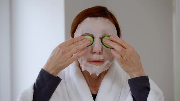 Front View Concentrated Woman in Moisturizing Mask Applying Cucumber Slices on Eyes