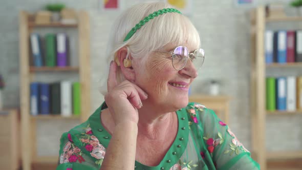 Surprised Joyful Old Woman Uses Hearing Aid for the First Time