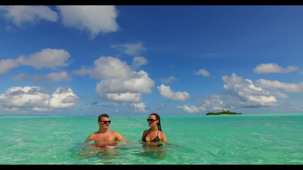 Family of two relax on idyllic island beach lifestyle by aqua blue sea and bright sandy background o