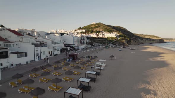 Aerial along the promenade of Salema showing comfortable beach beds, rental chairs and umbrellas