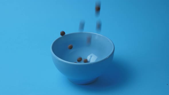 Chocolate breakfast cereals in balls are poured into a blue plate on a blue background