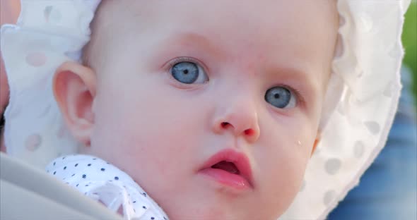 Slow Motion Close-Up Shot of Five Months Baby Girl Sitting Outdoors in a Stroller