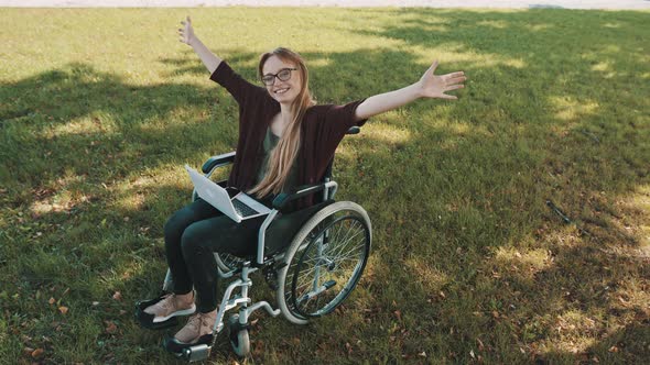 Happy Young Disabled Caucasian Woman in the Wheelchair Resting in the Nature with Laptop and