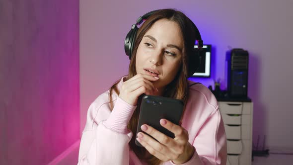 Relaxed Young Woman in Wireless Headphones Using Smart Phone Surfing Social Media Checking News