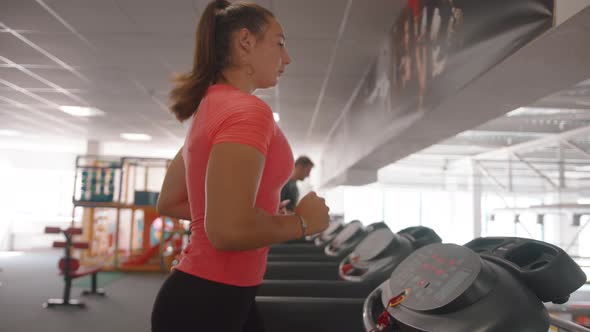 An Active Young Girl Runs on a Treadmill on a Cardio Workout in the Gym and Speeds Up the Fat