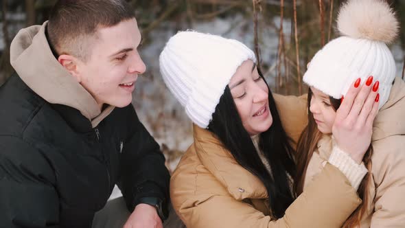 Parents with Daughter Walking in Forest in Winter