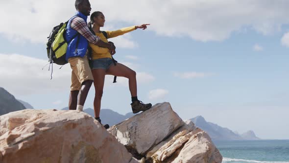 African american couple standing on the rocks enjoying the view while trekking