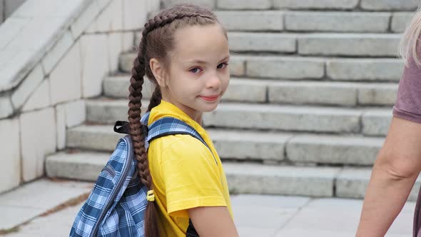 Girl with Plaits and Mommy Walk Up Stone Steps To School