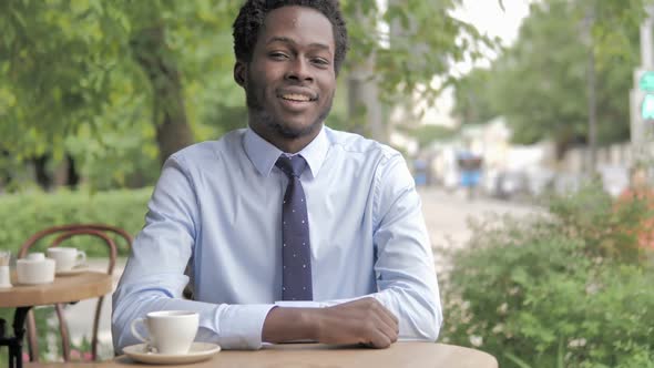 No African Businessman Shaking Head To Reject While Sitting in Outdoor Cafe