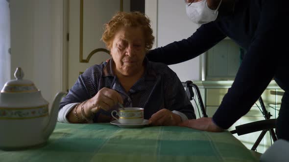 Elderly woman receives a visit from a young man with a mask.