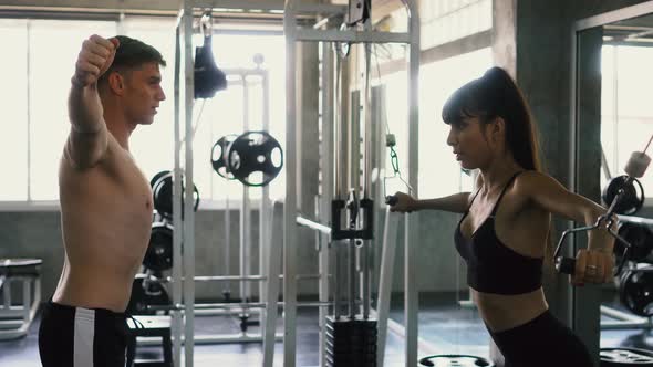 Sports Trainer Guiding Her Female Client Doing Cable Cross Over Chest Exercise at the Gym