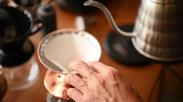 The barista is brewing coffee with traditional drip brewing equipment.