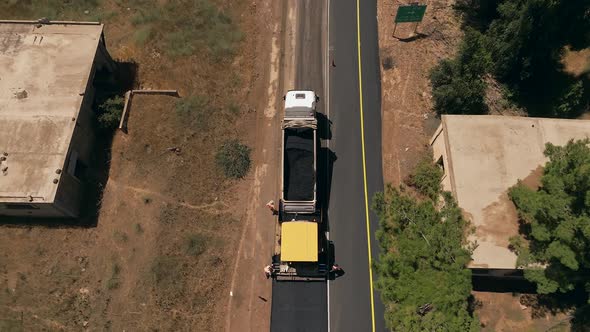 Asphalt paving machine escorted by an Asphalt truck at work, Top down aerial view.