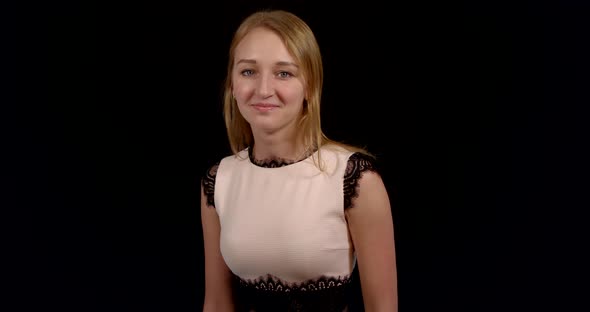 Charming Young Caucasian Female Is Posing Modestly in Black Background in Studio