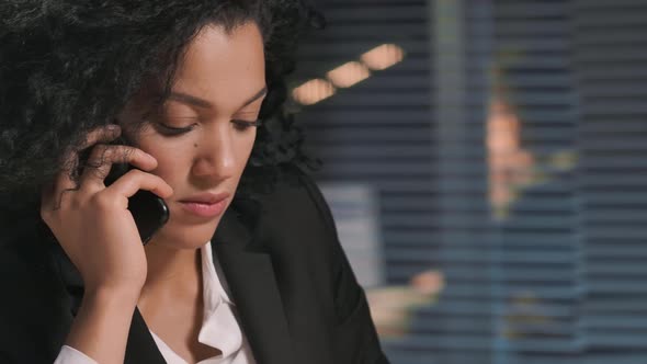 Portrait of African American Woman Talking on Smartphone and Makes Note on Piece of Paper