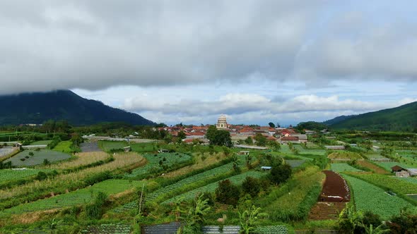 Aerial view of village and mosque amid rice fields by Mount Telomoyo, Indonesia