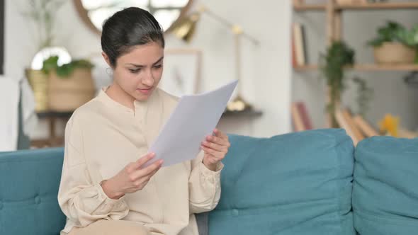 Indian Woman with Documents Reacting to Loss on Sofa