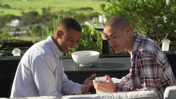 Friends discussing and using a smartphone on a rooftop