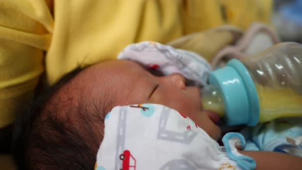 The newborn is eating breast milk from a bottle, slow-motion shot