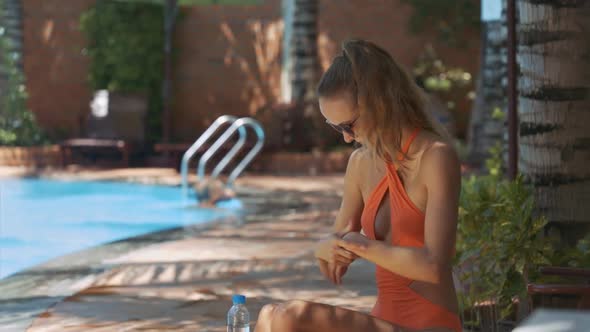 Woman in Bikini Uses Sunscreen for Arms By Pool