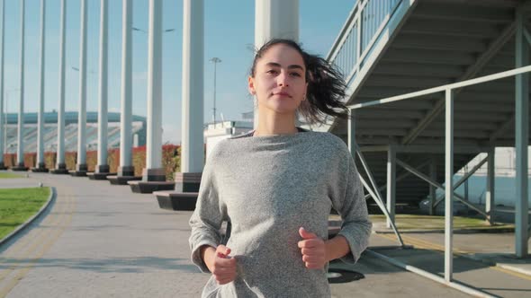 Pretty Brunette Lady Is Jogging Alone Outdoors, Frontal View on Face