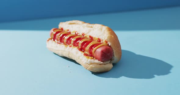 Video of hot dog with mustard and ketchup on a blue surface