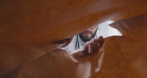 View From Inside Paper Bag of Young Male Doctor Taking Bananas for Lunch