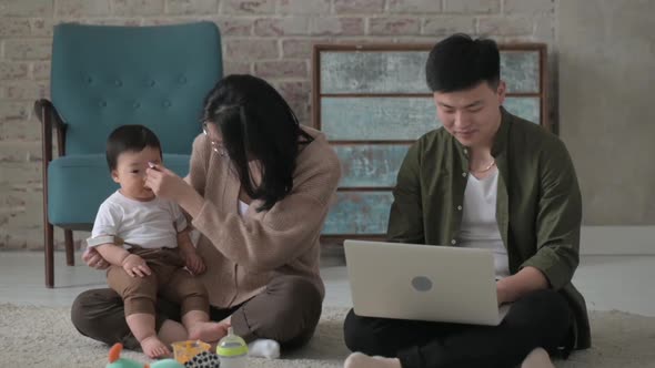 Asian family sitting on floor of cozy room with little boy 1 year.