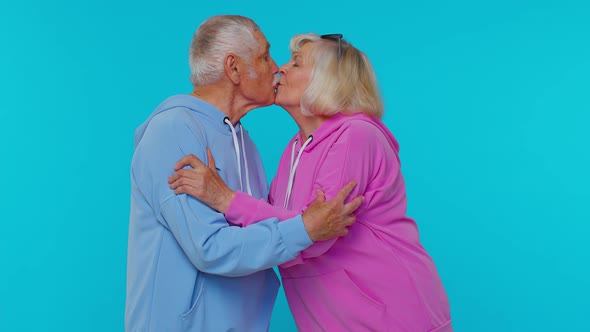 Romantic Senior Couple Man Woman Grandparents Making Lots of Kisses Looking at Camera and Smiling