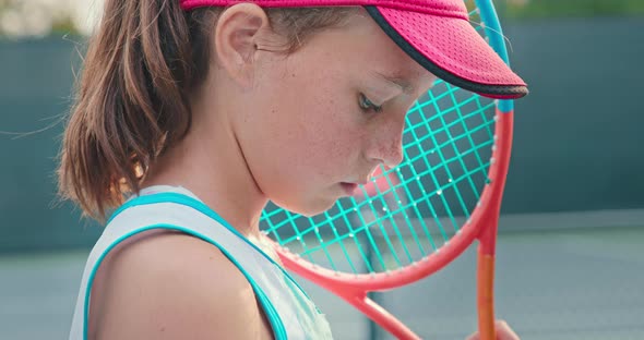 Young Blueeyed Girl Holds a Racket As She Looks Into Camera