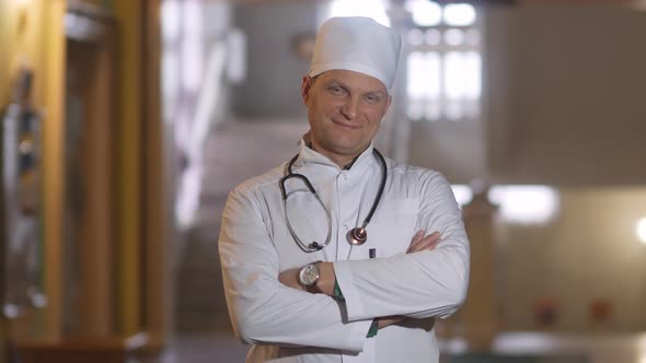 Portrait of a male smiling doctor satisfied with his work in a hospital corridor. The concept of med