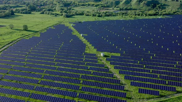 Aerial view on Solar Power Station in Green Field near River at Sunny Day