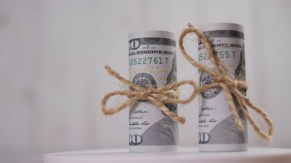A Stack of Hundreddollar Bills Tied with a Rope Rotates on a Light Background
