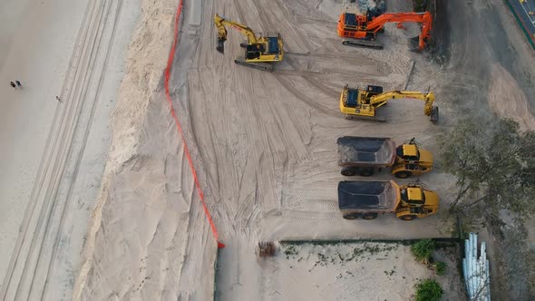 Large construction machinery used to repair sand dunes and beaches damaged by recent swell from a tr