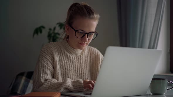 A Cheerful Young Girl Wearing Glasses Typing on a Laptop