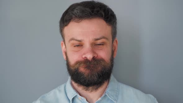 Bearded Man with Curled Up Mustache Eating Chocolate Chip Cookies on a Gray Wall Background