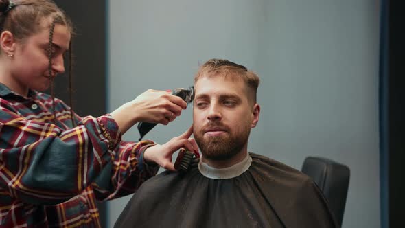 Barbershop: a woman barber cuts a client's man's hair