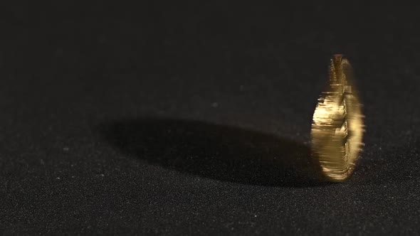 Golden bitcoin physical coin spinning over black