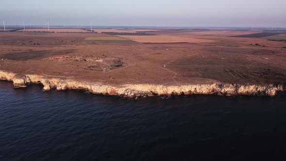 Drone top down aerial view of waves splash against rocky seashore, background. Flight over high clif