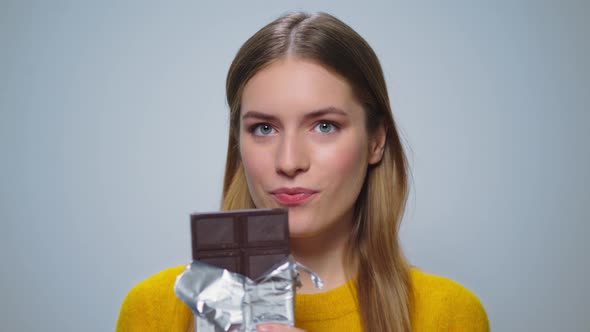 Portrait of Smiling Woman Looking with Chocolate Bar at Camera Indoors