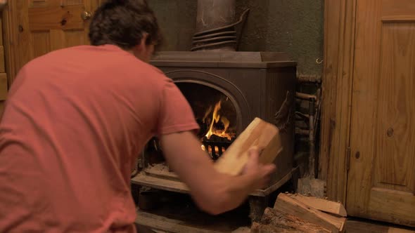 Loading wrought iron stove with silver birch logs self reliant young man