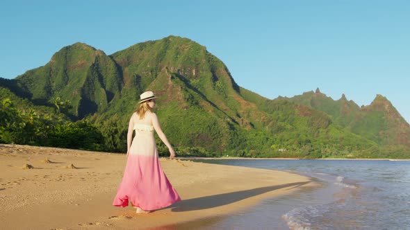 Woman in Pink Flattering Dress Walks By Beach on Kauai Tropical Island at Napali