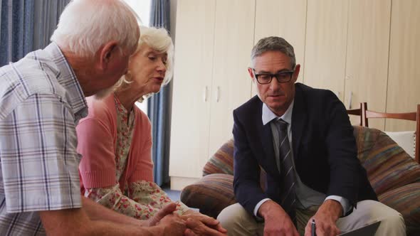 Senior couple talking with a business man in retirement house