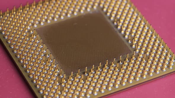 The Old Computer Processor CPU with Gold Plated Contacts Spins on Red Background