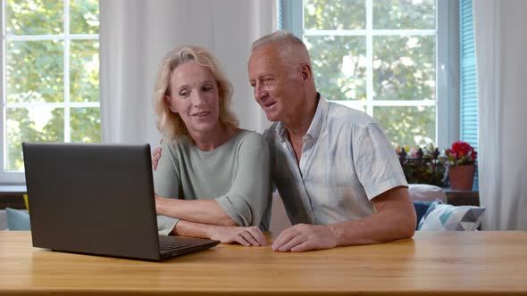 Happy Senior Couple Surfing Internet on Laptop Together at Home