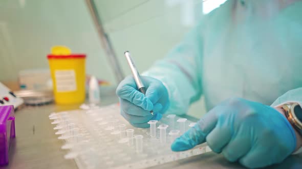 Laboratory worker writes with a pen on test tubes.