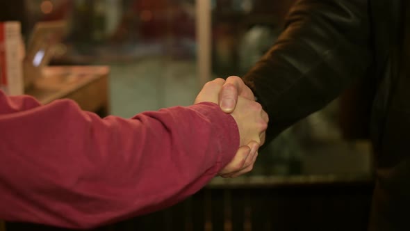 male handshake in a dark room of a smoky bar