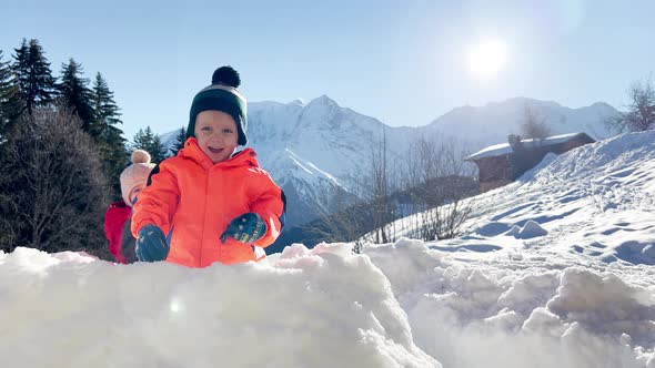 Little Boy with Baby Girl Stand in the Snow Fortress